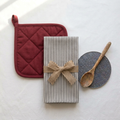 Example kitchen bundle with black and white striped towel, red pot holder, gray trivet, and wooden spoon